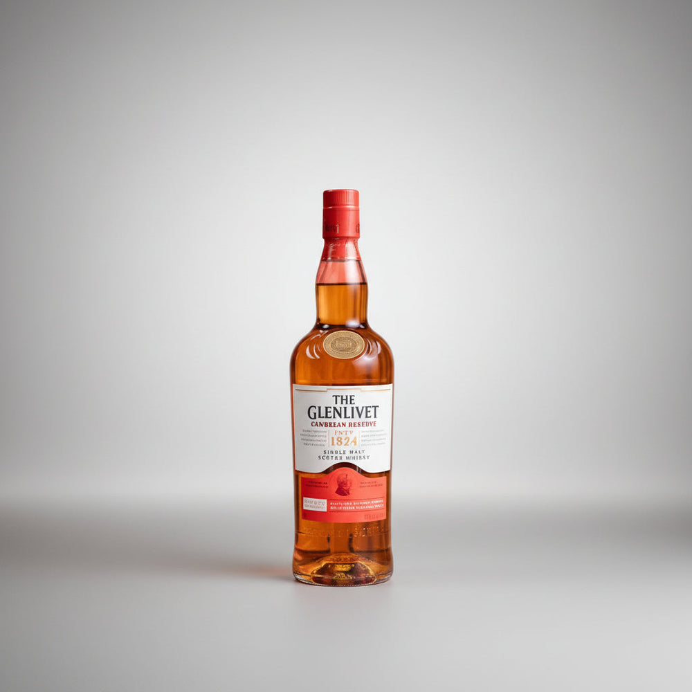 A bottle of The Glenlivet 1824 Single Malt Scotch Whisky stands on a small red pedestal against a plain white background, with decorative dried grass and a small white flower arrangement placed around it.